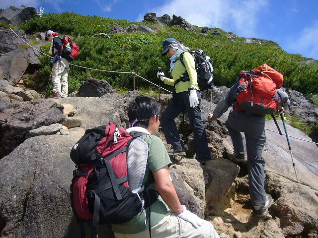 岩稜地帯のコースを一歩一歩確認しながら登る、全盲者である富山三つ星山の会 会長 坂田さん