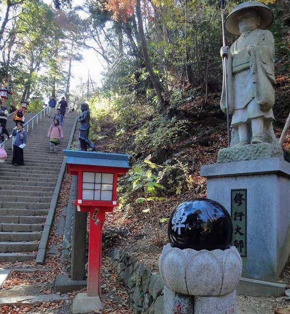 男坂の階段登り口には修行大師像が見守っています